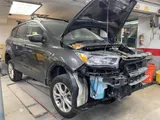 Ford Escape with heavy front-end collision damage, hood open in the shop