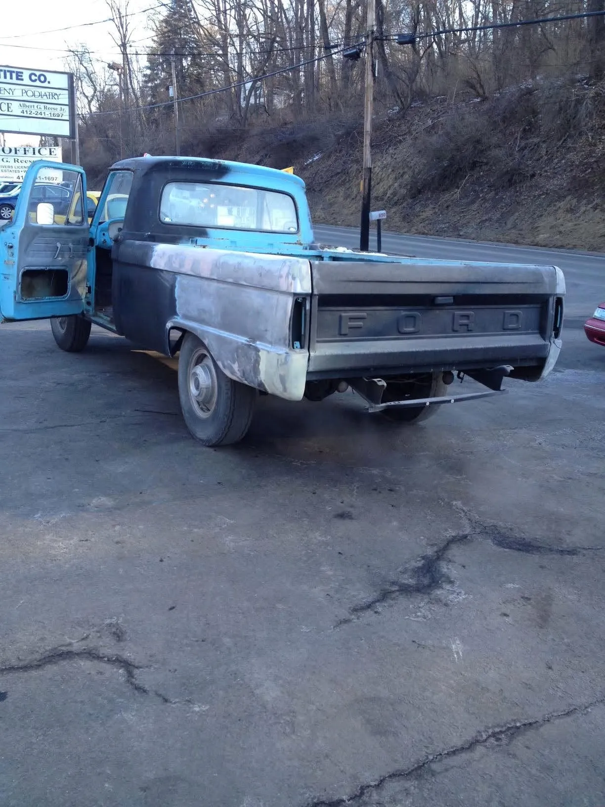 Classic Ford pickup stripped to bare metal outside the shop