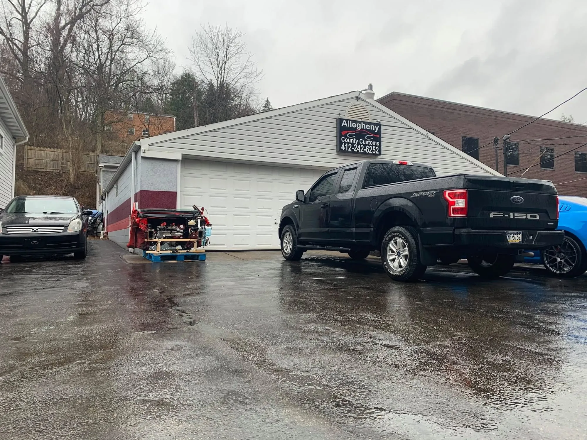 Side of the shop with a pickup and SUVs on the lot