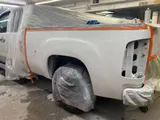Silver GMC Sierra bed masked for paint in the shop