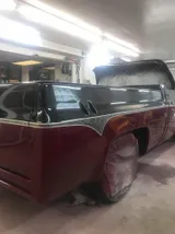Square-body Chevy pickup in the paint booth with fresh black and maroon paint
