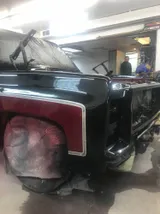 Rear of the two-tone Chevy pickup in the booth, wheels masked