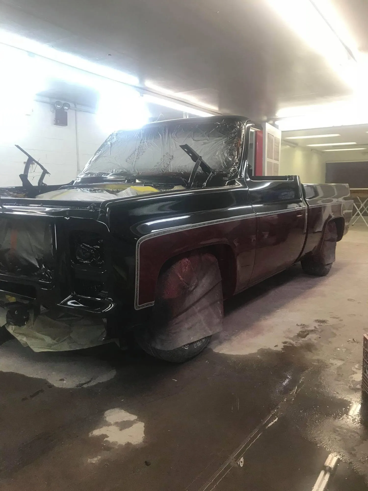 Side profile of the freshly painted pickup inside the shop
